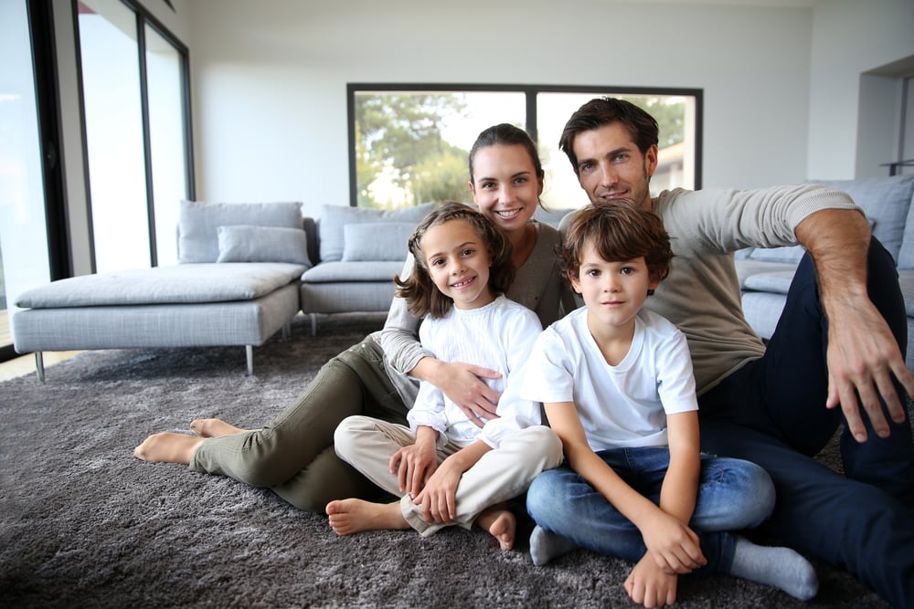 Happy family portrait at home sitting on carpet
